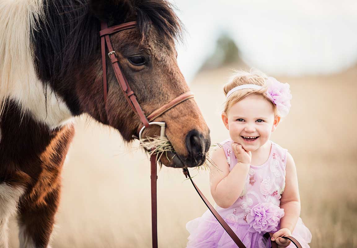 little girl with pony in purple dress
